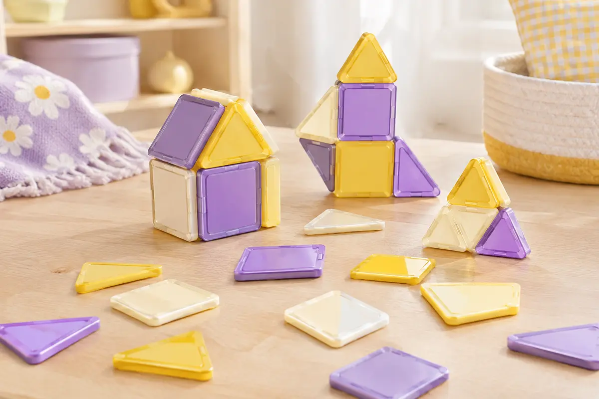 Pièces de construction magnétiques multicolores assemblées en formes géométriques sur un décor clair