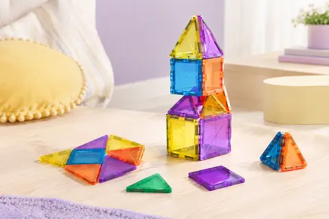 Tuiles magnétiques translucides colorées assemblées en petites constructions sur un fond doux