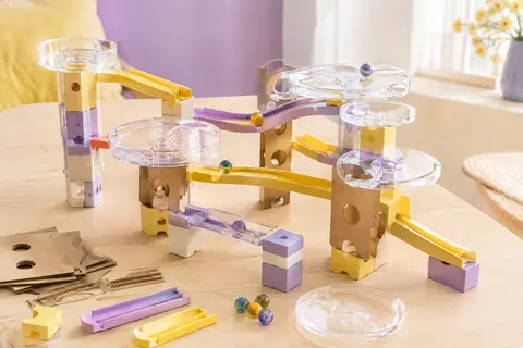 Circuit de billes à construire GraviTrax avec blocs, rails, plateformes transparentes et billes sur une table claire