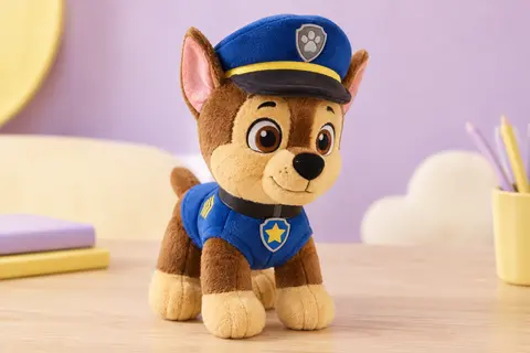 Peluche Chase de la Pat’ Patrouille d’environ 15 cm posée sur une surface en bois clair.