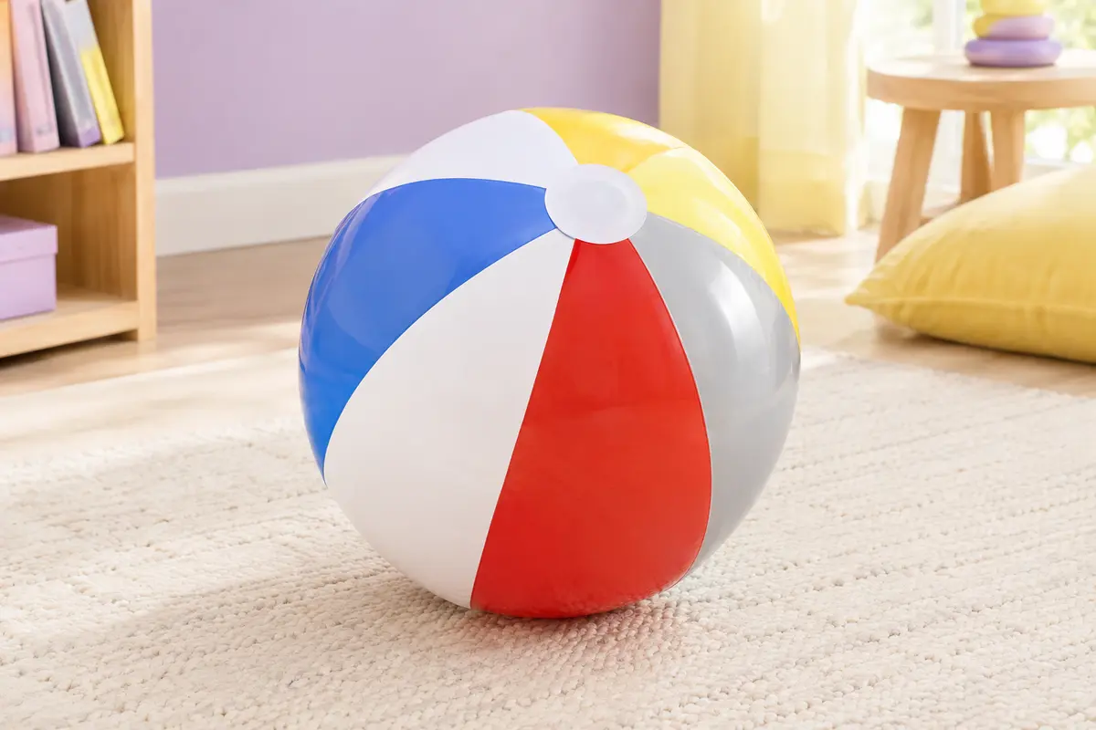 Ballon de plage Intex gonflable à panneaux brillants colorés posé dans un décor estival clair