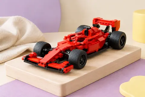 Voiture de course LEGO rouge assemblée, avec cockpit monoplace, aileron arrière et roues noires, posée sur du bois clair.