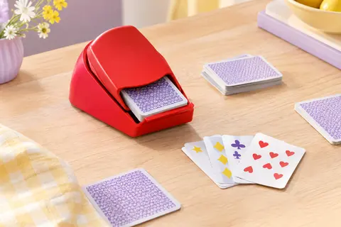 Lanceur rouge de jeu de cartes accompagné de cartes, posé sur une table en bois clair