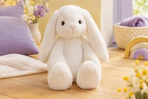 Peluche lapin blanc Melissa & Doug aux longues oreilles souples et à la fourrure douce, posée sur du bois clair.
