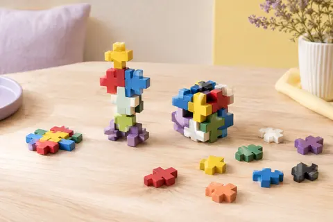 Pièces de construction Plus-Plus multicolores assemblées en motifs et en petite création sur un fond clair