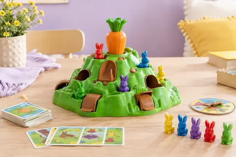 Jeu Croque Carotte avec colline multicolore, lapins et obstacles sur une table au décor lilas et crème.